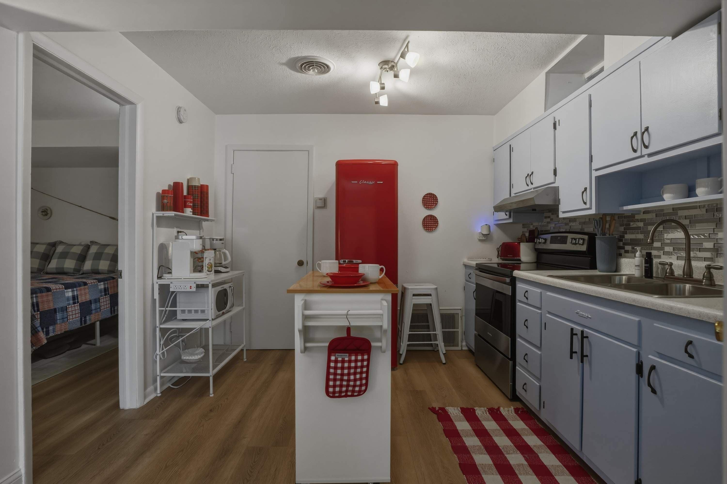 A compact kitchen with white cabinets, a red appliance, and a small dining area.