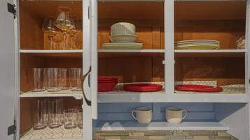A kitchen cabinet with wine glasses, plates, and cups.
