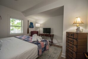 A bedroom with a bed, a desk, a television, and a dresser.