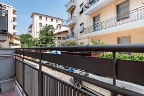 Um edifício residencial com varandas, portão fechado e um veículo estacionado.