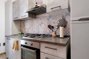 A kitchen with a gas stove, oven, stainless steel cabinets, and a patterned backsplash. - La Casetta di G&G Varese – Cozy Apartment near City Center and Stations (Varese)