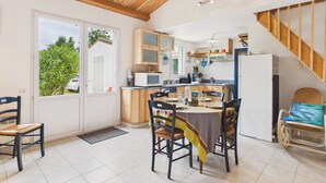 Eine Küche mit Holzschränken, einem Esstisch mit Stühlen, einem Kühlschrank und einer Treppe zu einer weiteren Ebene.