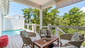 A covered outdoor area with a pool, wicker furniture, and a view of trees. - Fin and Tonic - Private Pool + 6 Bikes (Inlet Beach)