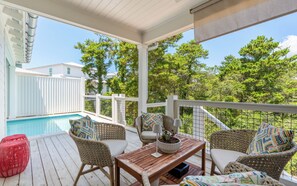 A covered outdoor area with a pool, wicker furniture, and a view of trees. - Fin and Tonic - Private Pool + 6 Bikes (Inlet Beach)