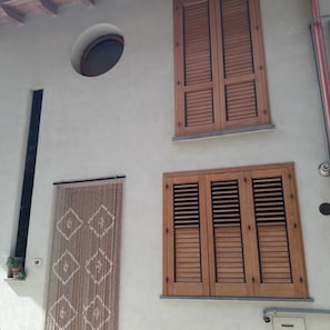 A building with two wooden shutters, a vertical pipe, and a circular window.
