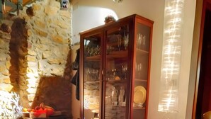 Une pièce avec un mur en pierre, un meuble en bois doté de portes en verre et un sol carrelé.