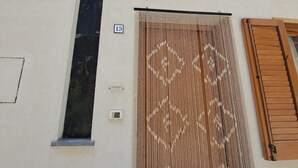 Une façade d’immeuble ornée d’une grande fenêtre verticale, d’une fenêtre circulaire et d’une porte avec un rideau à motifs.