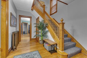 Eine Holztreppe mit einer Sitzbank, einem Heizkörper und einem Blumentopf in einer Diele.
