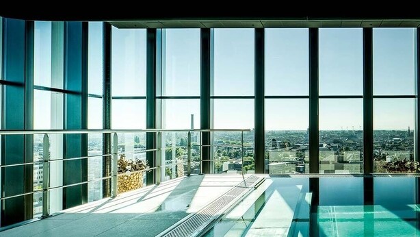 A modern indoor swimming pool with large windows offering a city view.
