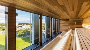 Moderni sisustus, jossa on suuret ikkunat, puiset penkit ja näkymä kaupunkimaisemaan.