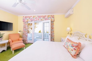 Un dormitorio con cama, una silla, una mesita, una lámpara y un ventilador de techo.
