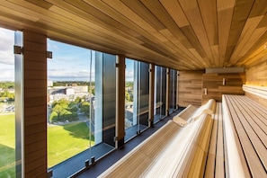 Un interno moderno con ampie finestre, panche in legno e vista sulla città.