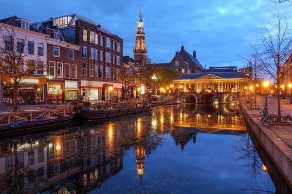 Stroll canalside at dusk, surrounded by glowing city lights.