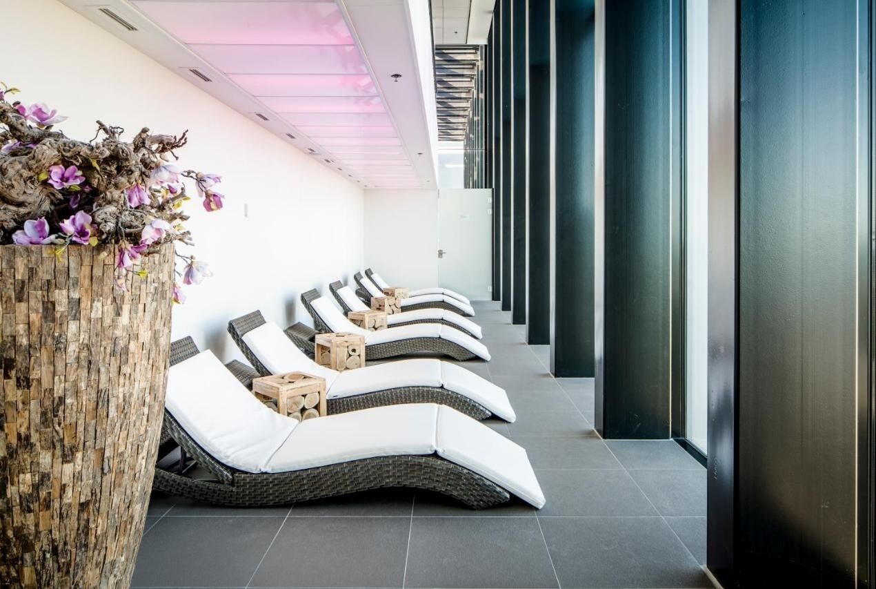 Un espace spa moderne doté de fauteuils inclinables, d’un élément décoratif en bois et d’un mur en verre.