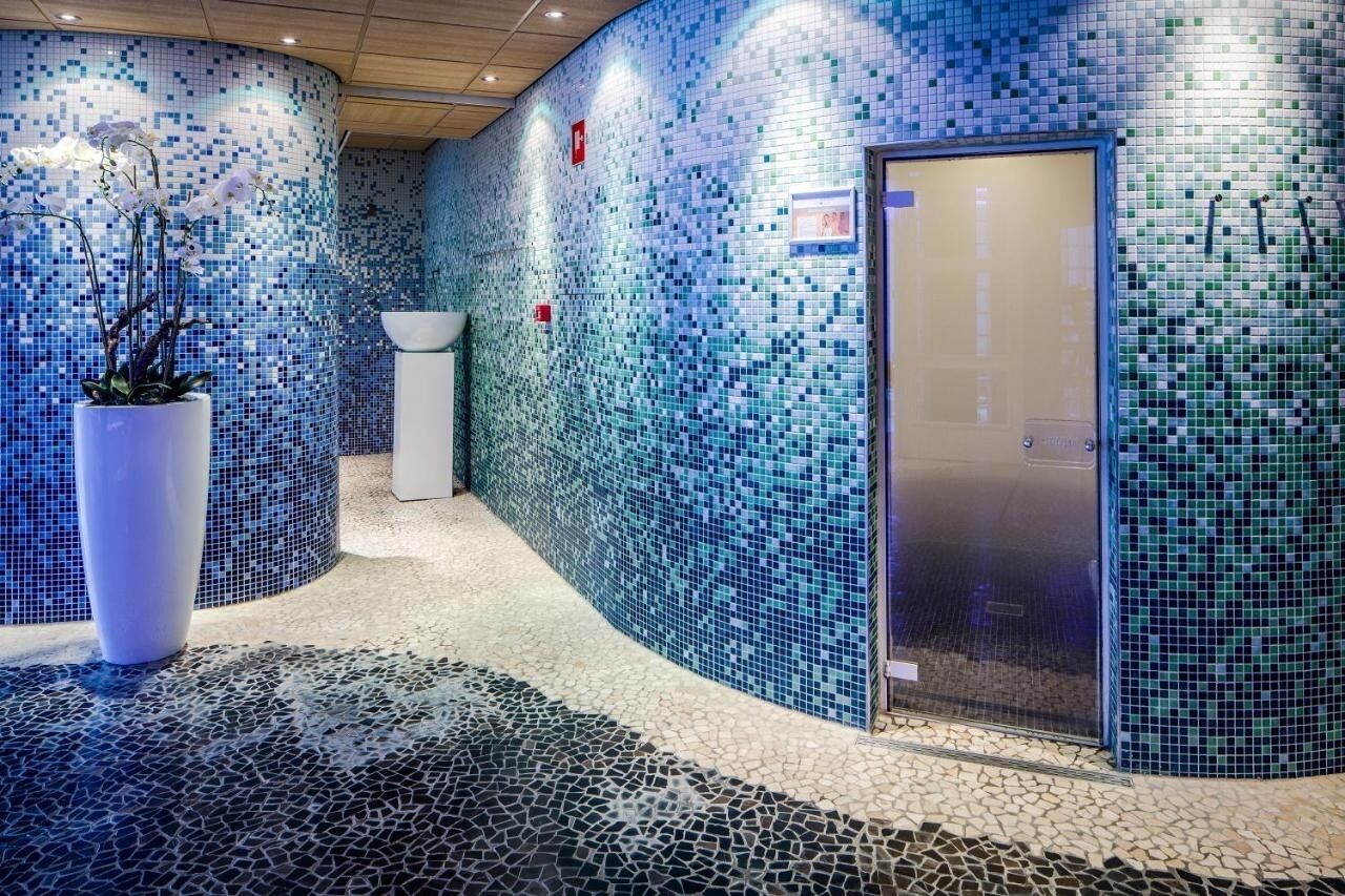 Eine Lobby mit Mosaikwänden, einem Empfangstresen und einer Zimmerpflanze.
