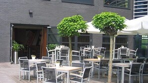 An outdoor patio with tables and chairs, trees, and a building in the background. - Experience Comfort and Wellness! Indoor Pool, Near Beeradvertising Museum! (Etten-Leur)