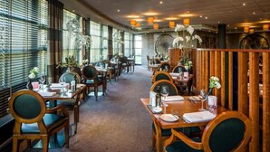 A restaurant with wooden tables and chairs, large windows, and decorative plants. - Experience Comfort and Wellness! Indoor Pool, Near Beeradvertising Museum! (Etten-Leur)