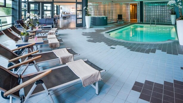 A poolside area with lounge chairs, a reception desk, and a pool. - Experience Comfort and Wellness! Indoor Pool, Near Beeradvertising Museum! (Etten-Leur)