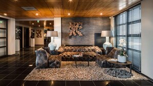 A modern lobby with a leather sofa, two side chairs, a round coffee table, and a large abstract wall art piece.