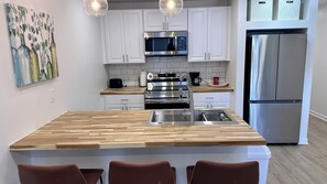 A modern kitchen with a central island, stainless steel appliances, and white cabinetry.