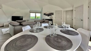 A dining area with a round table, white chairs, and woven placemats.