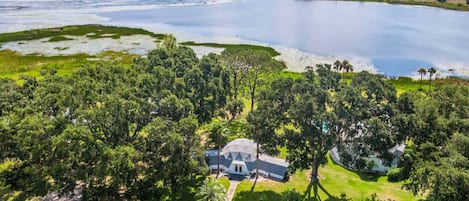 Een huis omgeven door dichte bomen en een groot wateroppervlak.