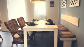 Ein Essbereich mit Korbstühlen, einem weißen Tisch und einer Bank.