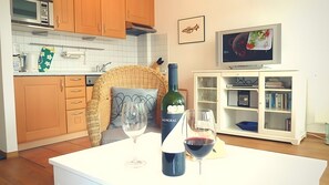 Een keuken met houten kastjes, een magnetron, een televisie en een wijnfles op het aanrecht.