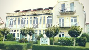 Ein mehrstöckiges Hotel mit Balkonen, einer Schautafel und gepflegter Bepflanzung.