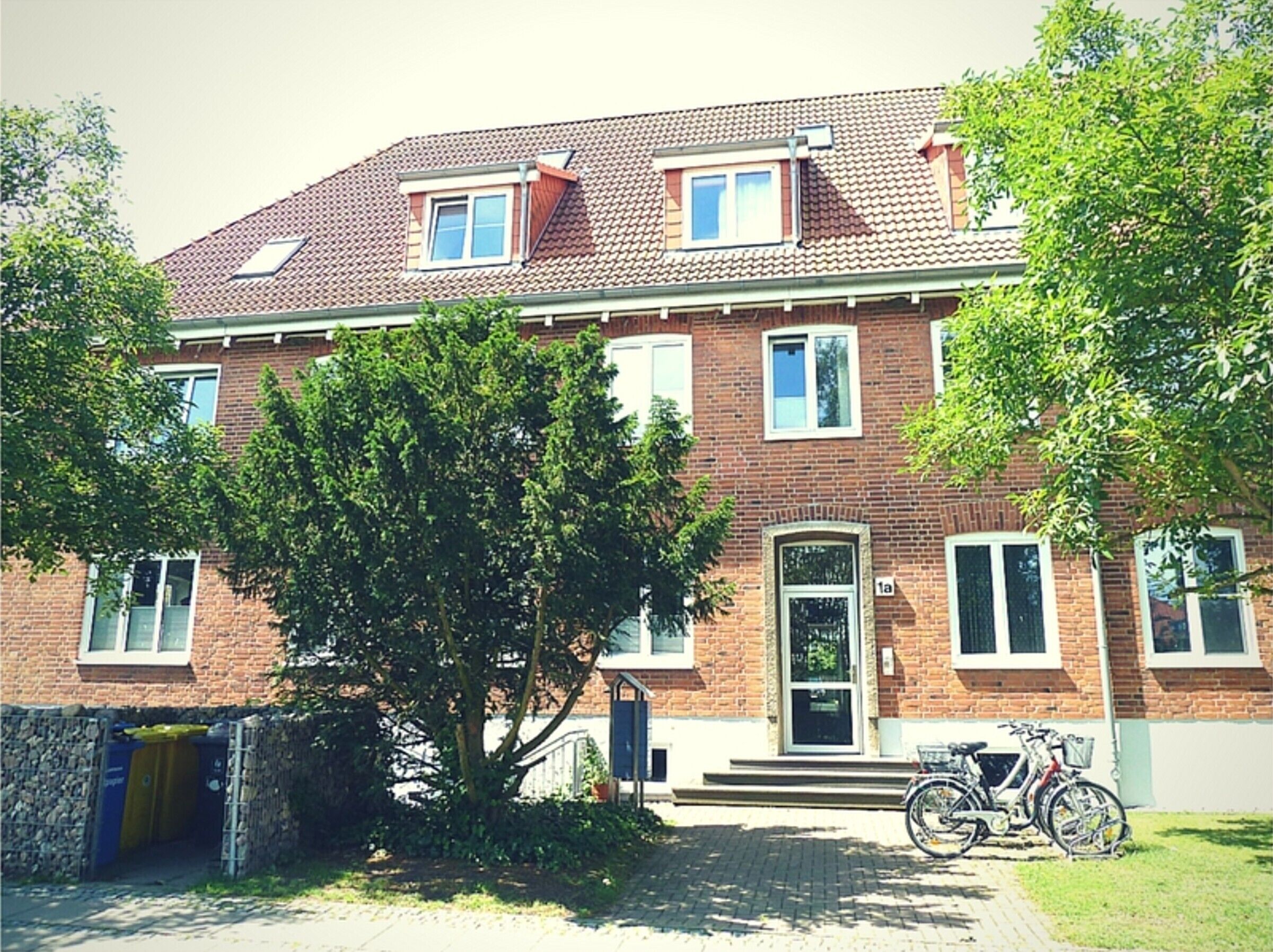 Ein zweistöckiges Backsteinhhaus mit Ziegeldach, einer Haustür und einem Fahrrad davor.