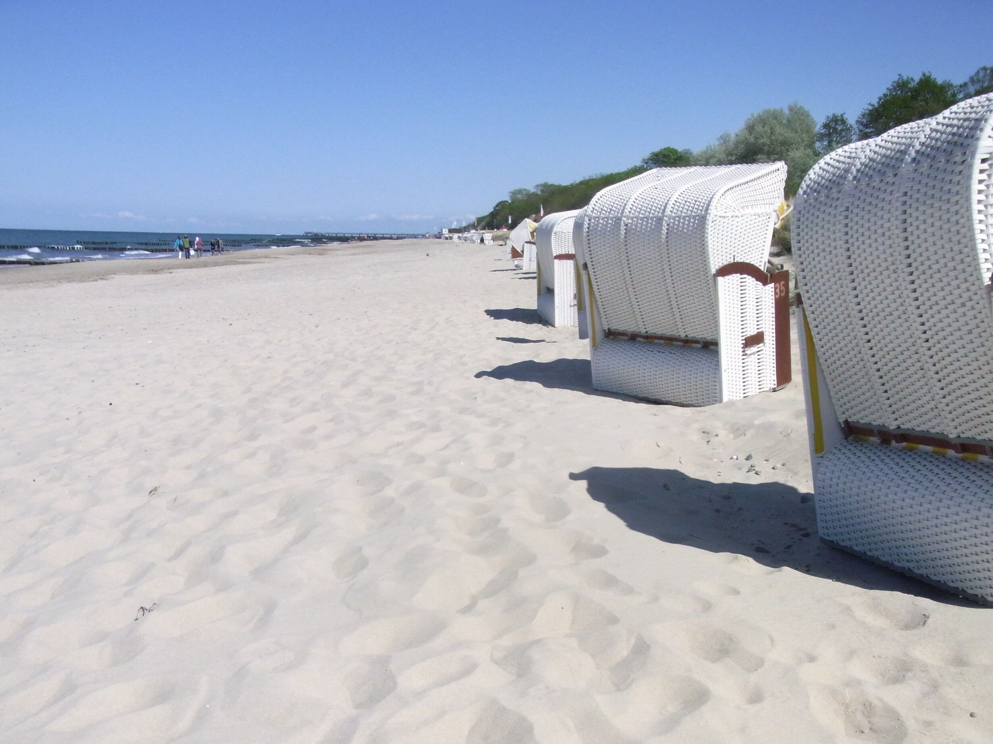 Ein Strand mit Reihen aus weißen Liegestühlen und freiem Blick auf den Ozean.