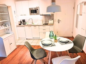 Una cocina moderna con armarios blancos, microondas y una mesa para dos personas.
