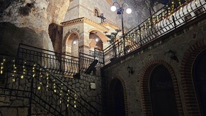Un bâtiment en pierre doté d’un escalier, d’une rambarde en métal et de guirlandes lumineuses.
