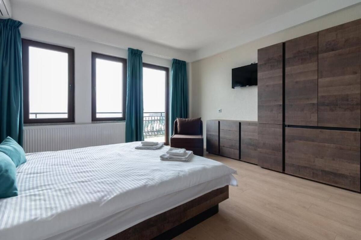 Un dormitorio con cama, una silla, televisor y armario.