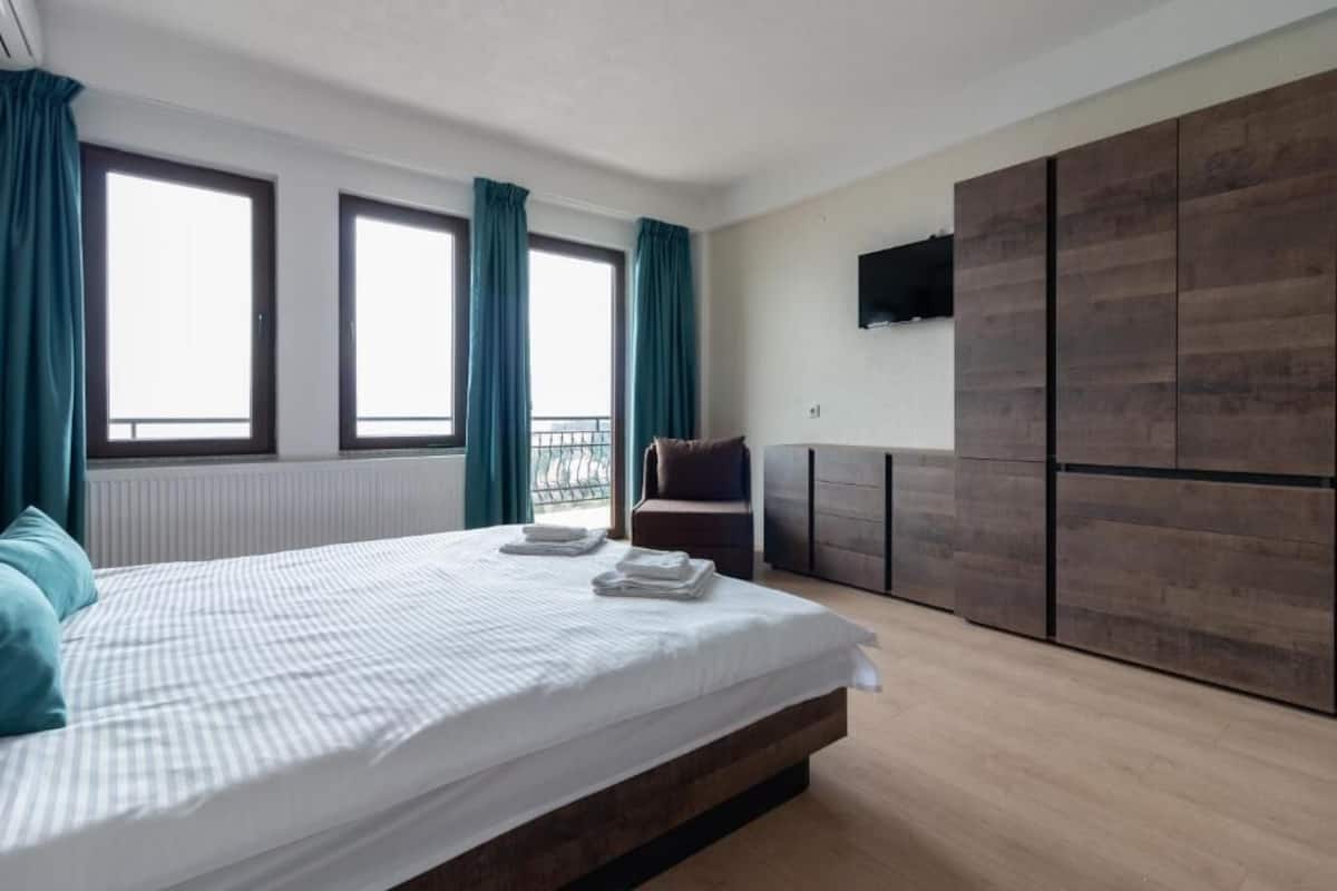 Un dormitorio con cama, una silla, televisor y armario.