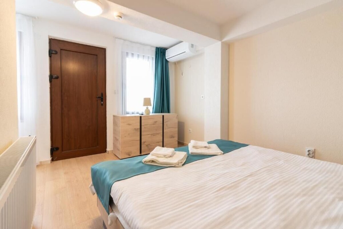Un dormitorio con cama, cómoda, puerta y equipo de aire acondicionado.