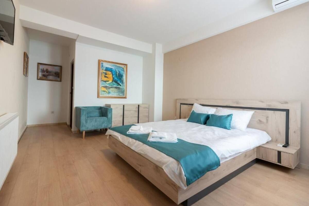 Un dormitorio moderno con una cama grande, una mesita de noche, una silla y un cuadro en la pared.