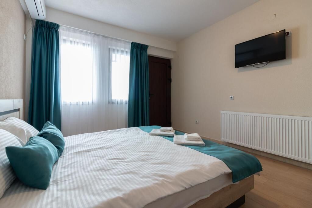 Una habitación de hotel con cama, cortinas, televisión y radiador.