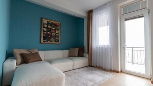 Une chambre moderne avec un canapé-lit, un tableau encadré au mur et un balcon offrant une vue dégagée.