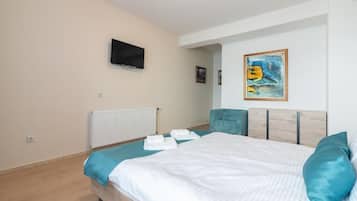 A bedroom with a bed, a television, a painting, and a radiator.
