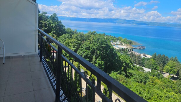 Un balcon offrant une vue sur une zone côtière, notamment une plage et une étendue d’eau.