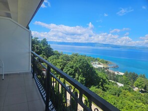 A balcony with a view of a coastal area, including a beach and a body of water.