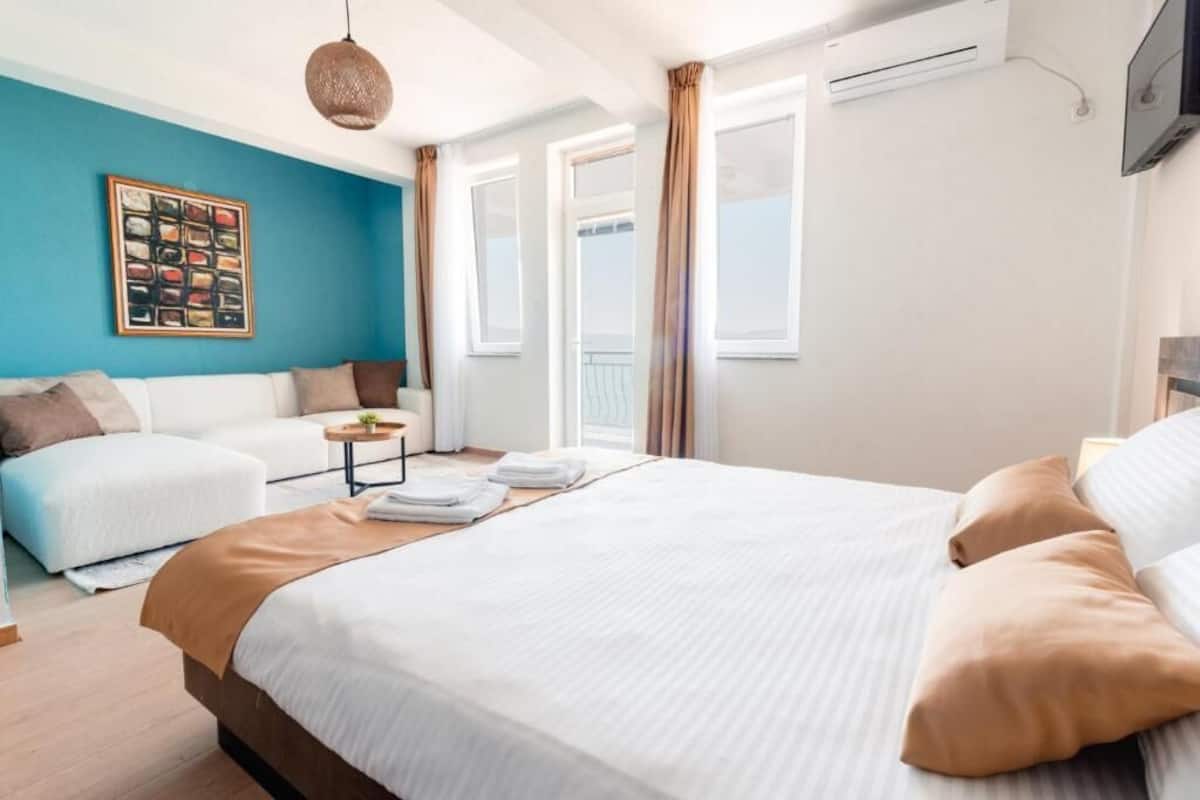 Una habitación de hotel con cama, sofá, una mesita y televisor de pared.