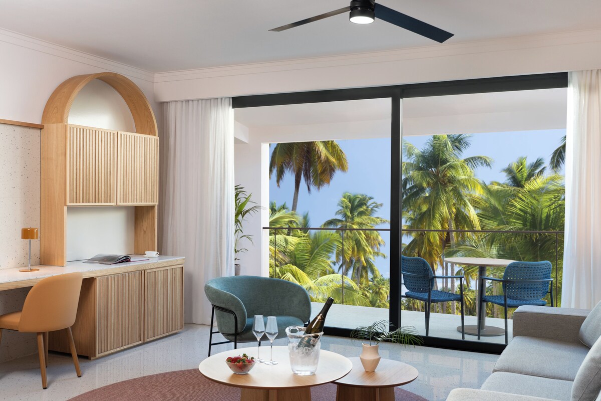 A modern living room with a balcony, a desk, and seating area.