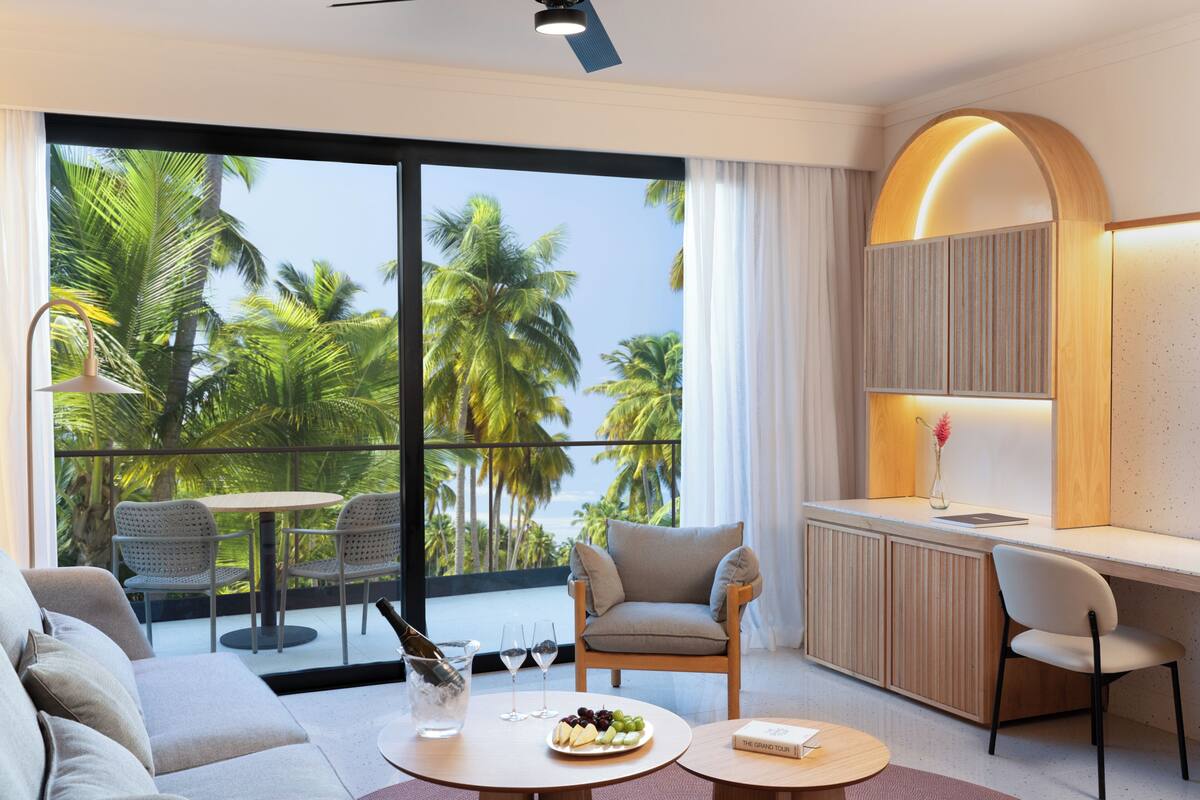 Una habitación de hotel moderna con balcón, sofá, mesa de comedor y zona de cocina.