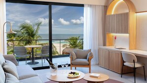 Une chambre d’hôtel moderne dotée d’un balcon, d’un canapé, d’une table à manger et d’un espace bureau.