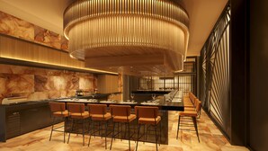 Un restaurant moderne doté d’une longue table à manger, de nombreuses chaises, d’un bar central et d’un grand luminaire circulaire.