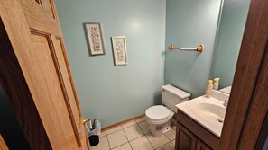 Un bagno con il water, un lavandino e due opere d'arte incorniciate appese al muro.