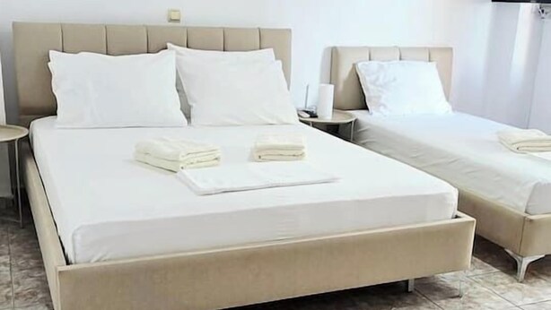 Een hotelkamer met twee bedden, een flatscreentelevisie en een airconditioning.