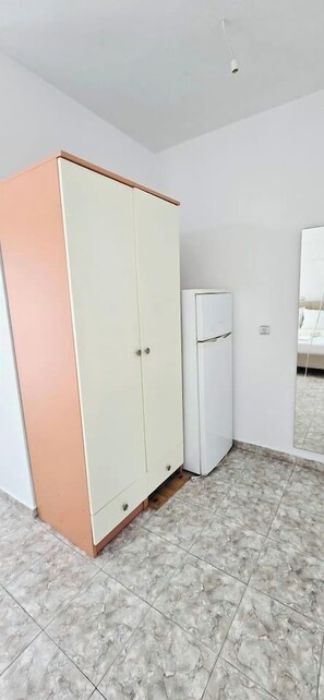 A room with a wardrobe, a refrigerator, and a tiled floor. - PH Azure Horizon Residences G/2 (Saranda)